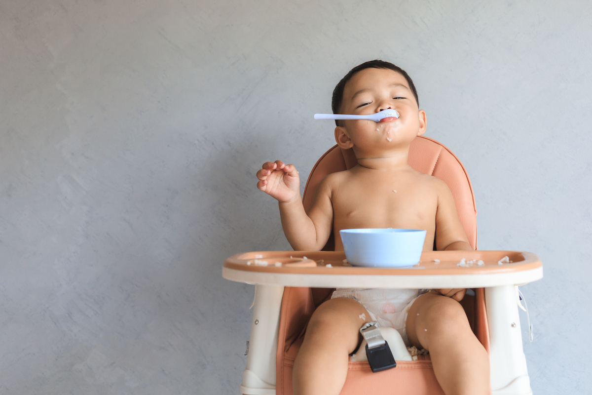 http://kidseatincolor.com/wp-content/uploads/2022/08/Baby-in-High-Chair-with-Spoon-in-Mouth.jpg