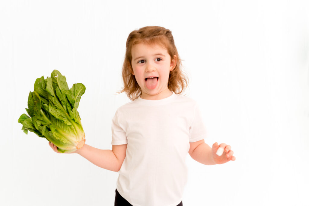 A Child with a distaste look toward a vegetable