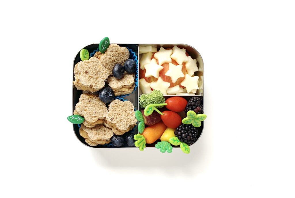 Cute lunchbox featuring a sandwich cut up in flower shapes with a side of fruit