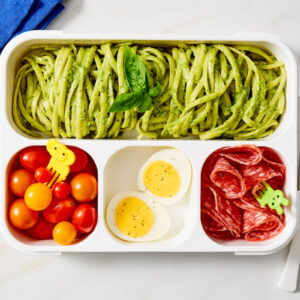 Green noodles with sides in bento-style lunchbox