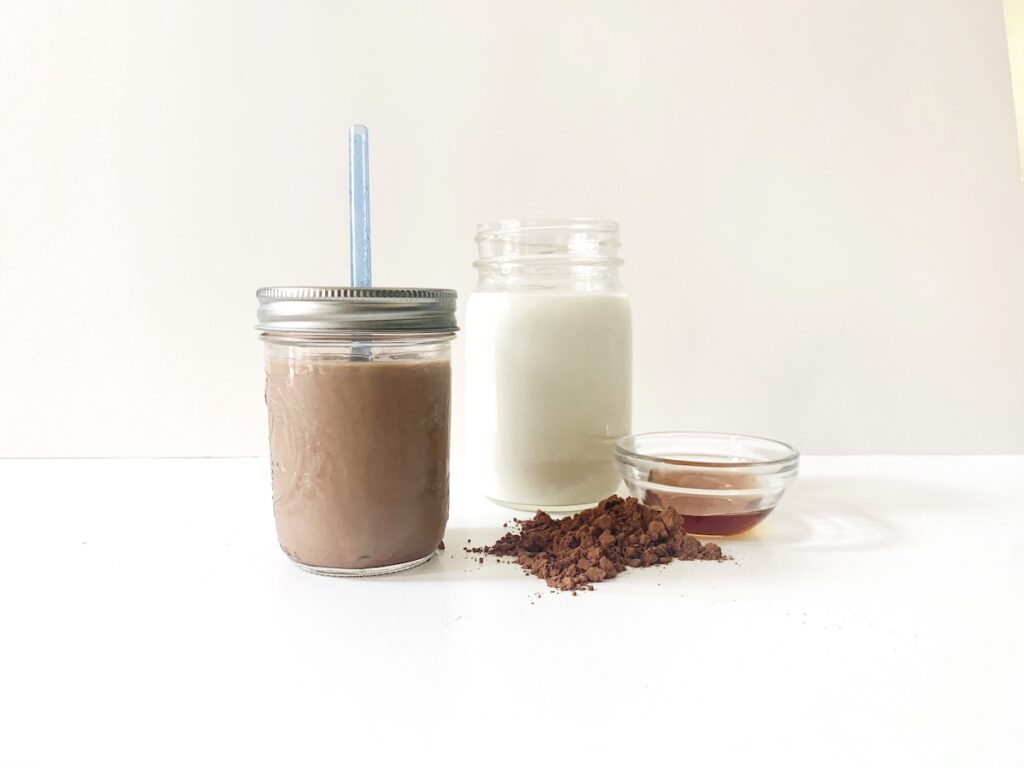 Glass of homemade chocolate milk and ingredients