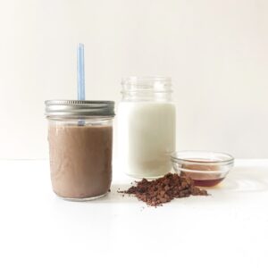 Glass of homemade chocolate milk and ingredients