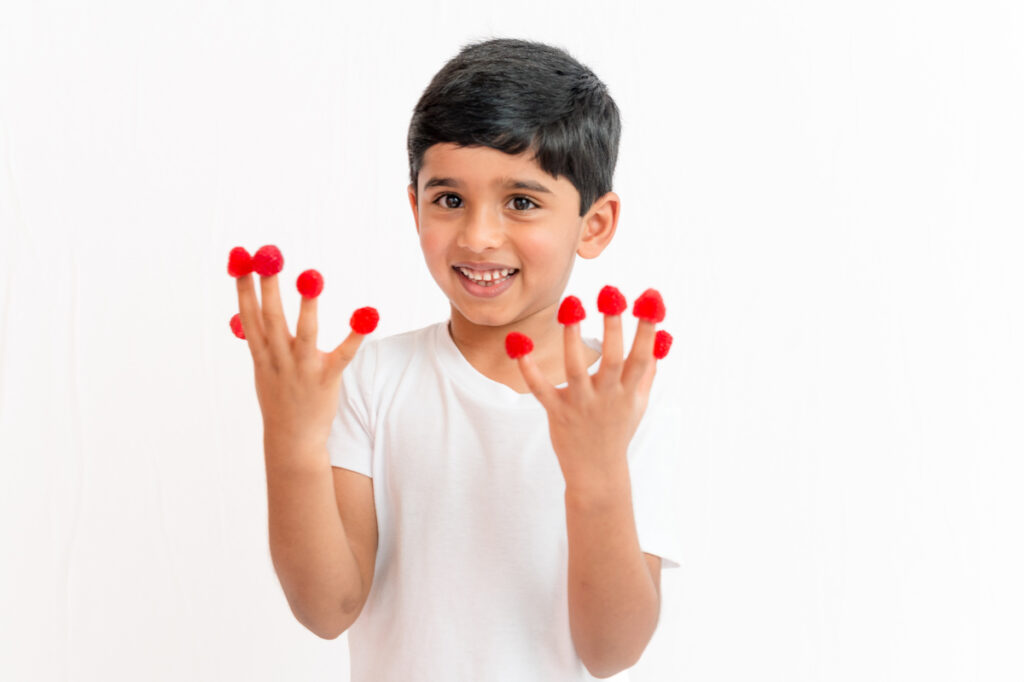 Child with raspberries on their fingers
