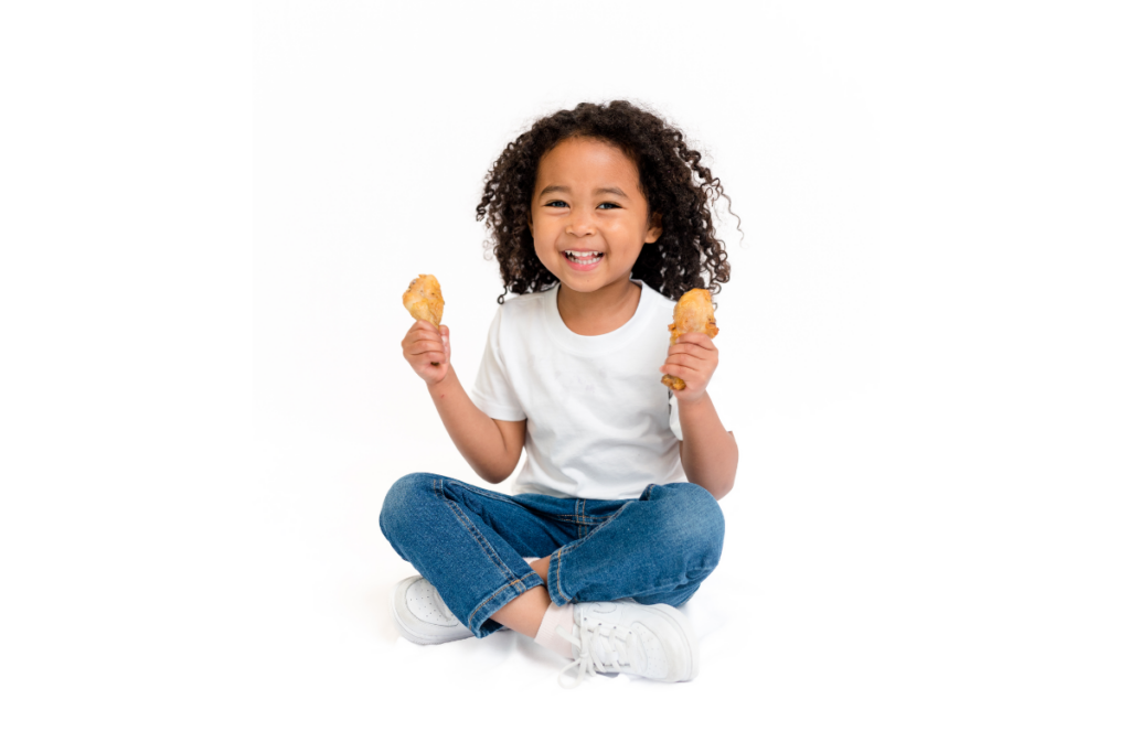 Child holding protein-filled drumsticks in hands