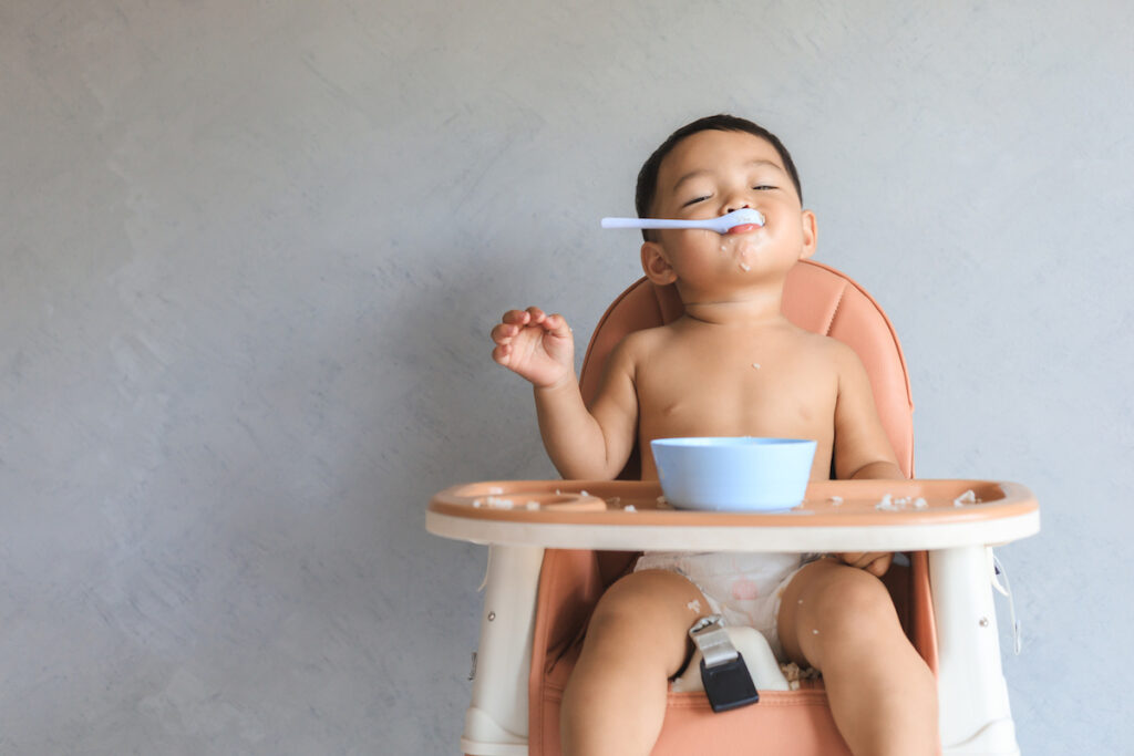 https://kidseatincolor.com/wp-content/uploads/2022/08/Baby-in-High-Chair-with-Spoon-in-Mouth-1024x683.jpg