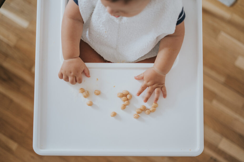 Baby with chickpeas sitting in high chair