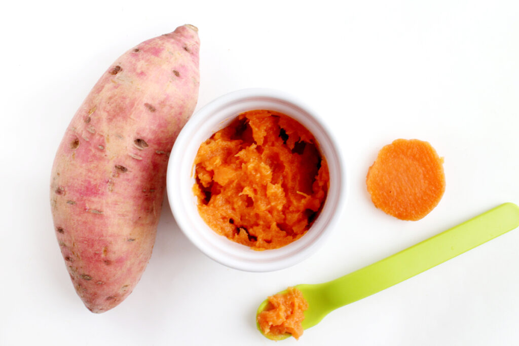 Mashed sweet potato in bowl with baby spoon