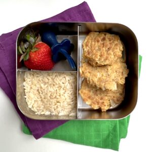 Three tuna tofu patties into a bento lunchbox with rice and a strawberry