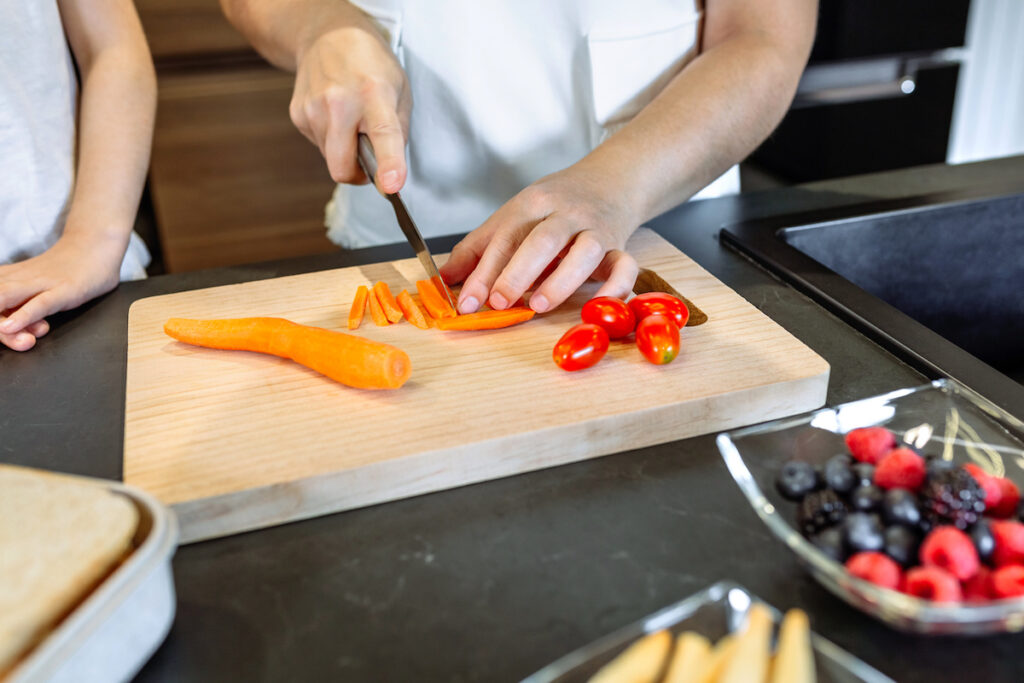 Chopping carrots and tomatoes to demonstrate choking prevention tools