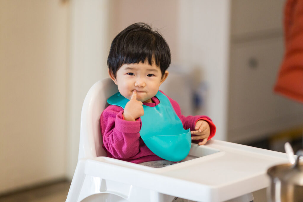 Child wearing a silicone baby bib in their high chair