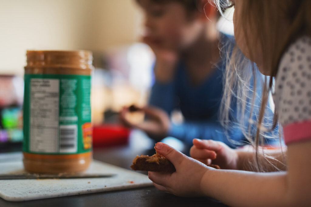 Toddler and child eating peanut butter