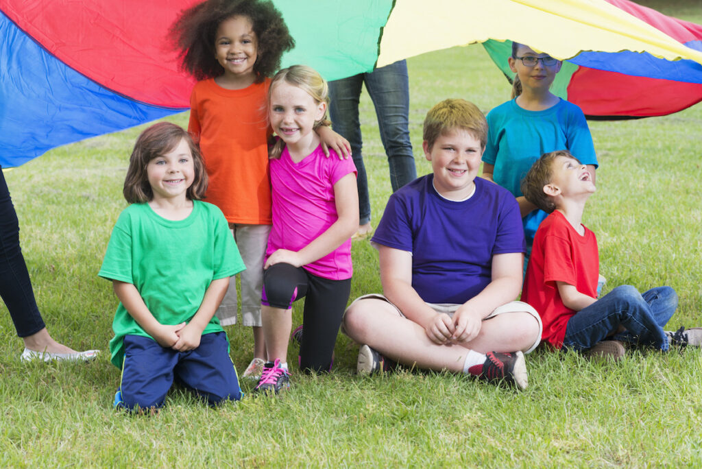 A group of children outside playing with a parachute