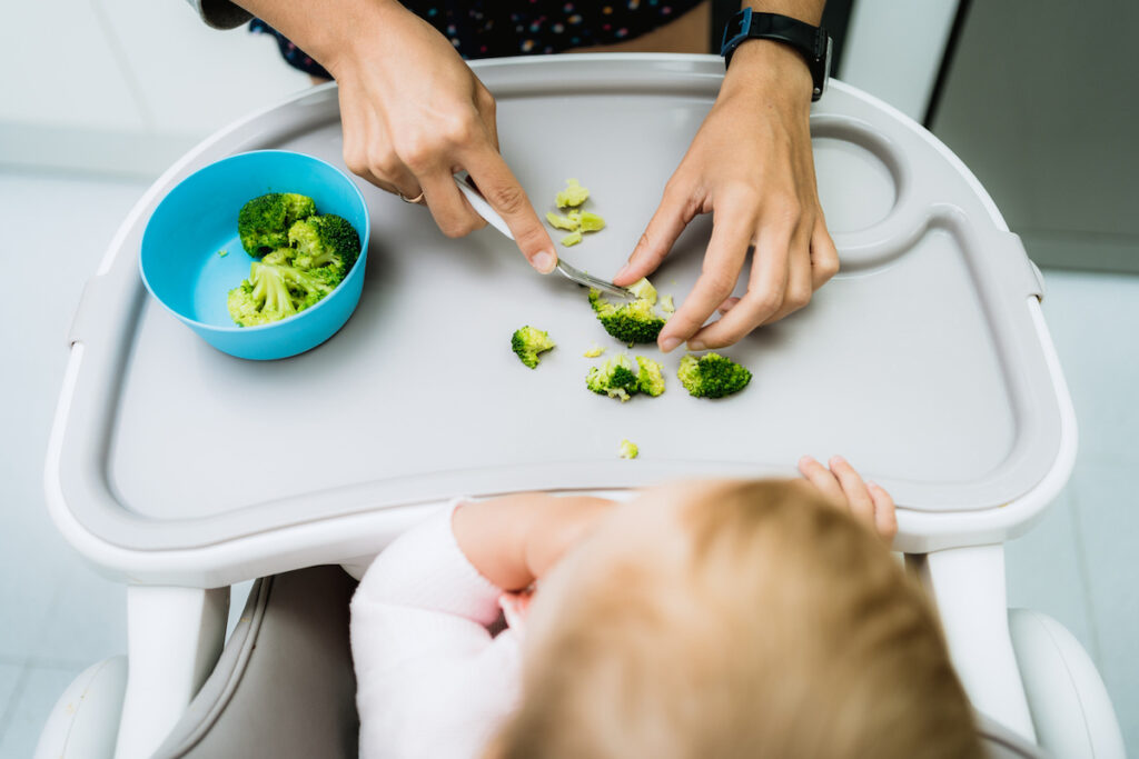 Mom cuts broccoli for baby according to baby-led weaning method