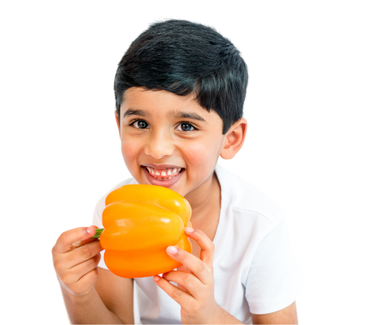 Boy smiling and holding an orange bell pepper